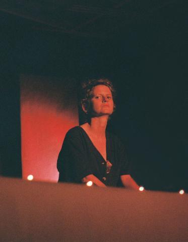 Jemima Foxtrot standing in front of red background, in profile