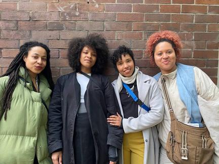 four smiling persons in front of a brick wall